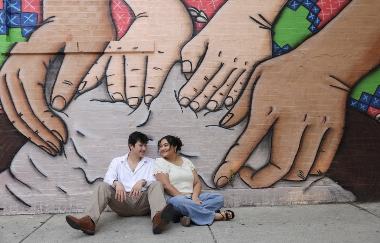 Ethan and Elli sitting under a mural of hands